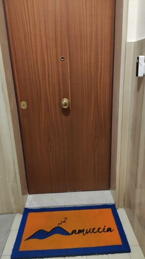 A wooden door with a brass handle and a small hole above it. - Mamuccia Rooms (Naples)