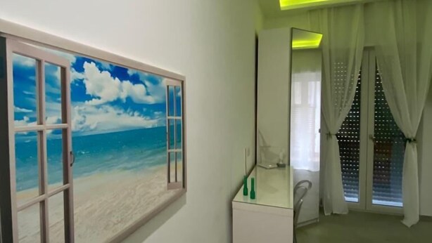 A modern bathroom with a beach mural, a glass shower enclosure, and a ceiling with green LED lighting. - Mamuccia Rooms (Naples)