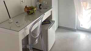 A modern kitchen with a white countertop, a built-in fridge, a glass dining table, and a TV mounted on the wall. - Mamuccia Rooms (Naples)