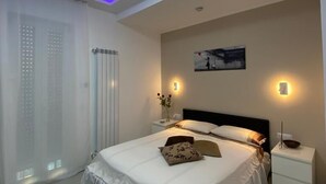 A modern bedroom with a bed, bedside tables, and a ceiling light fixture. - Mamuccia Rooms (Naples)