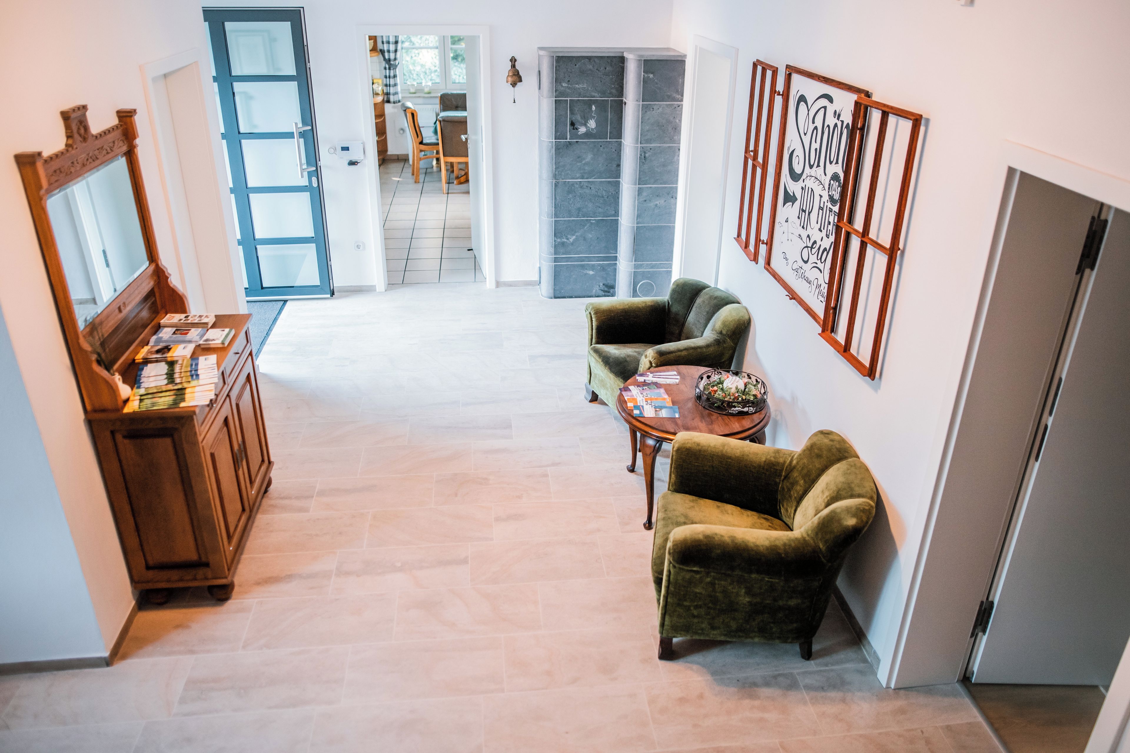 Una habitación amplia con un armario de madera, dos sillones, una mesita y un espejo grande.