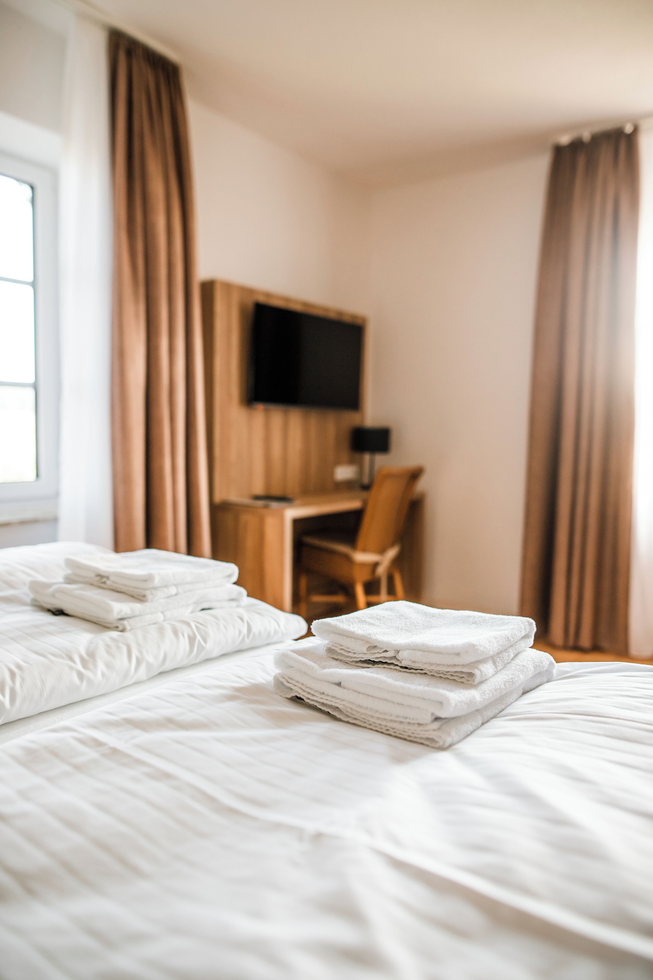 Ein Hotelzimmer mit Bett, Schreibtisch und Fernseher.