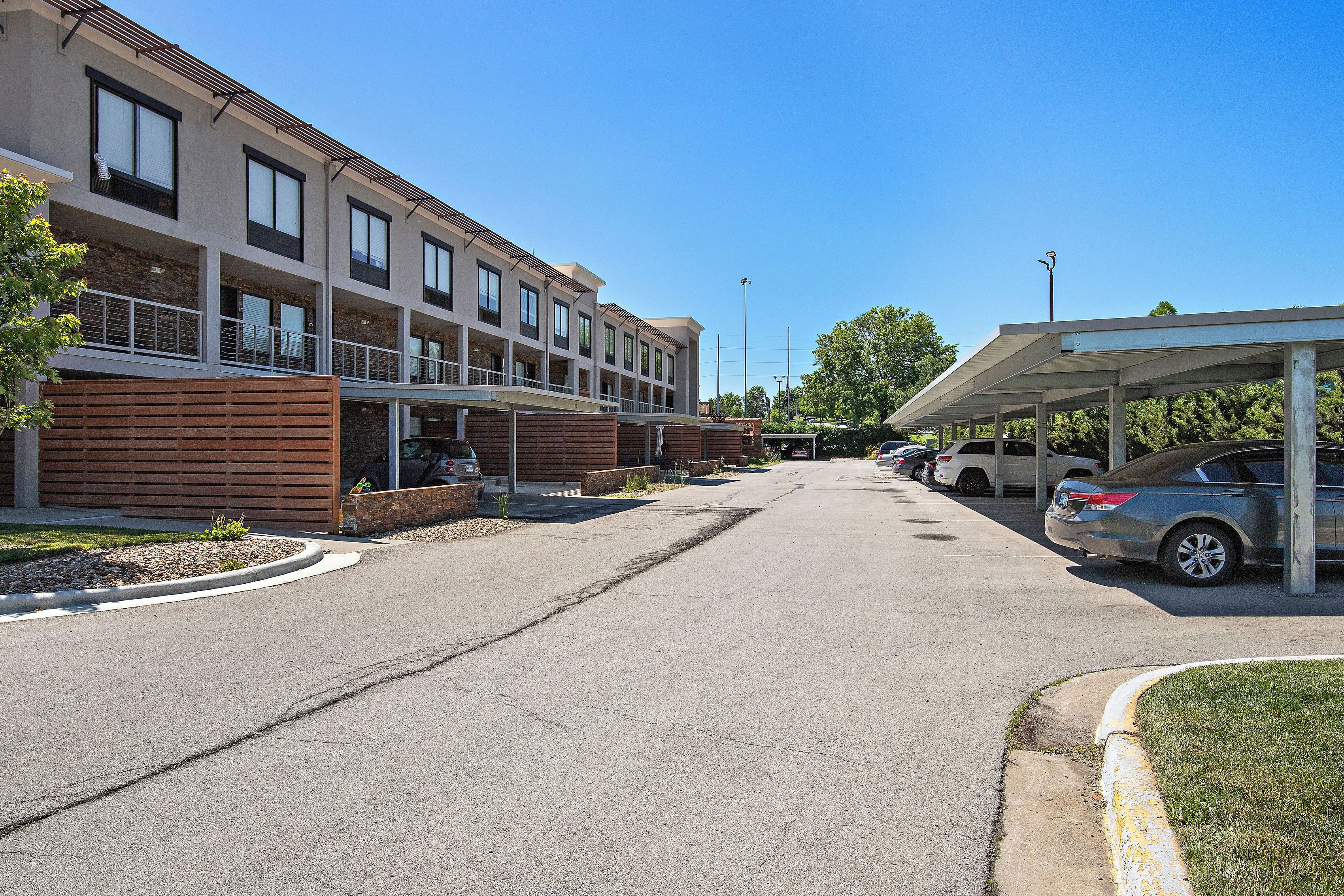 A multi-story building with balconies, a covered parking area, and a clear sky.