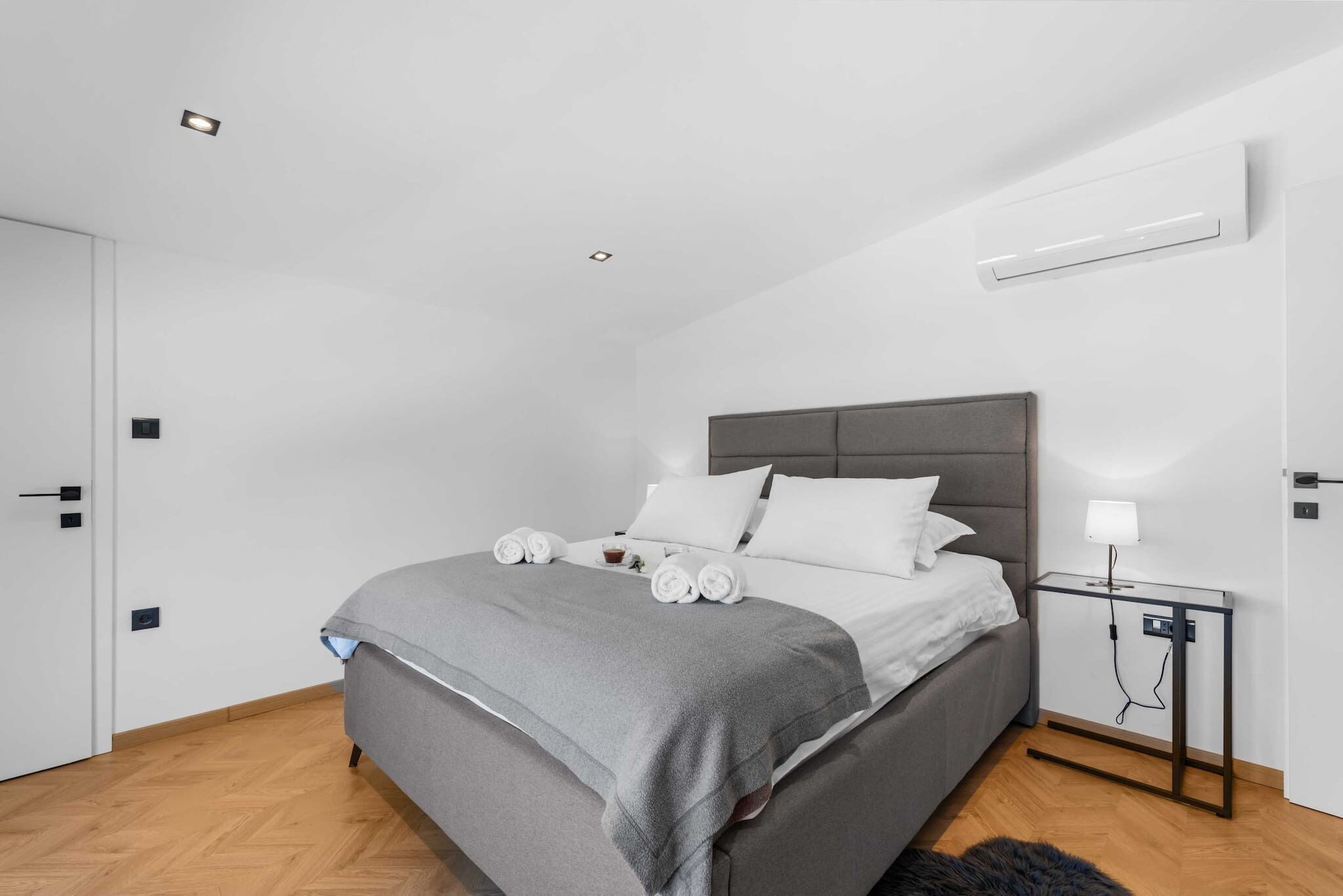 Ein modernes Schlafzimmer mit Bett, Nachttisch und Klimaanlage.
