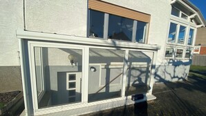 A building with a large window and a door with a security lock. - Newly renovated basement apartment (Rodenbach)
