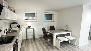 A modern kitchen with white cabinets, a built-in oven, and a dining area with a table and chairs. - Newly renovated basement apartment (Rodenbach)