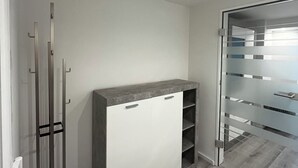 A modern room with a grey cabinet, a glass door, and a wooden floor. - Newly renovated basement apartment (Rodenbach)