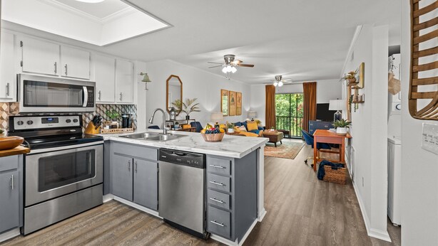 A modern kitchen with stainless steel appliances, a central island, and a dining area with a view.