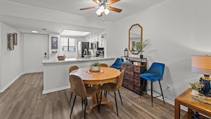 A modern kitchen with white cabinets, a central island, and a ceiling fan.