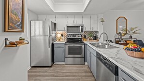 A modern kitchen with a skylight, stainless steel appliances, and a marble countertop.