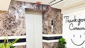 A reception area with a marble wall, a white elevator, and a 'Thank you' sign with a smiley face. - Bensri Residence Pattaya (Pattaya)