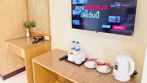 A hotel reception area with a television displaying a Netflix interface in multiple languages, a coffee maker, and a counter with a remote control, water bottles, and a tissue box. - Bensri Residence Pattaya (Pattaya)