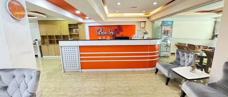 A reception area with a modern design, featuring a reception desk, seating area, and a clock on the wall.