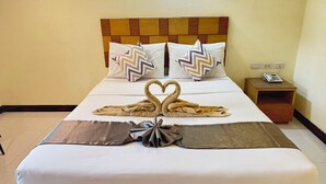 A hotel room with a bed, two pillows, a bedside table with a phone, and a wall socket. - Bensri Residence Pattaya (Pattaya)