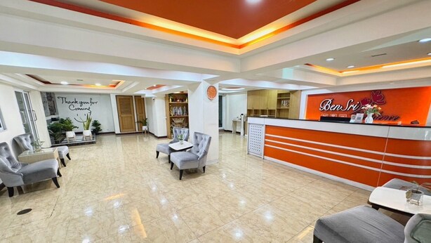 A reception area with a modern design, featuring a reception desk, seating area, and a decorative wall with a clock. - Bensri Residence Pattaya (Pattaya)