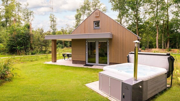 A modern outdoor hot tub area with a wooden structure, a covered seating area, and a hot tub. - Detached wellness accommodation for 4 people (Gasselte)
