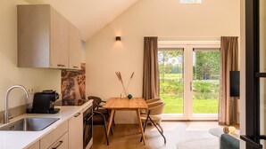 Een moderne keuken met een houten tafel, stoelen en een groot raam met gordijnen.