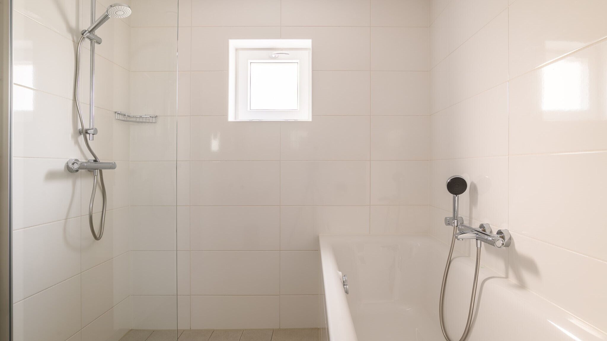 Un baño con ducha, bañera y ventana.