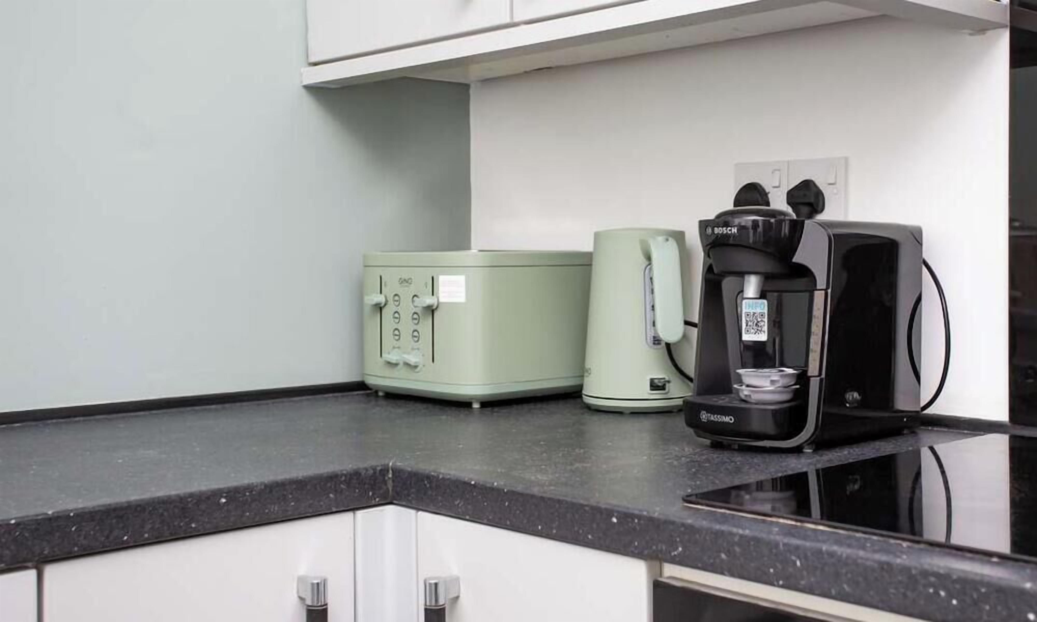 A kitchen with a toaster, a coffee maker, and a microwave on a black countertop.