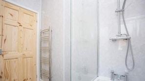 A bathroom with a wooden door, a glass shower enclosure, and a showerhead. - Meldon Terrace | Parking | Wi-Fi (Northumberland)