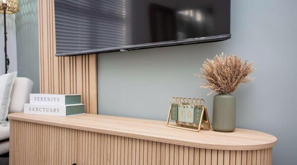 A reception desk with a mounted TV, a vase with dried plants, and a calendar.