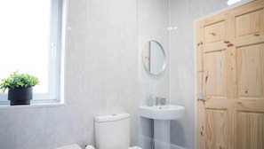 A bathroom with a toilet, sink, mirror, and wooden door.