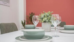 A dining table set with green plates, clear wine glasses, and a potted plant.