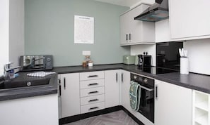 A compact kitchen with white cabinets, a microwave, a toaster, and a coffee maker.
