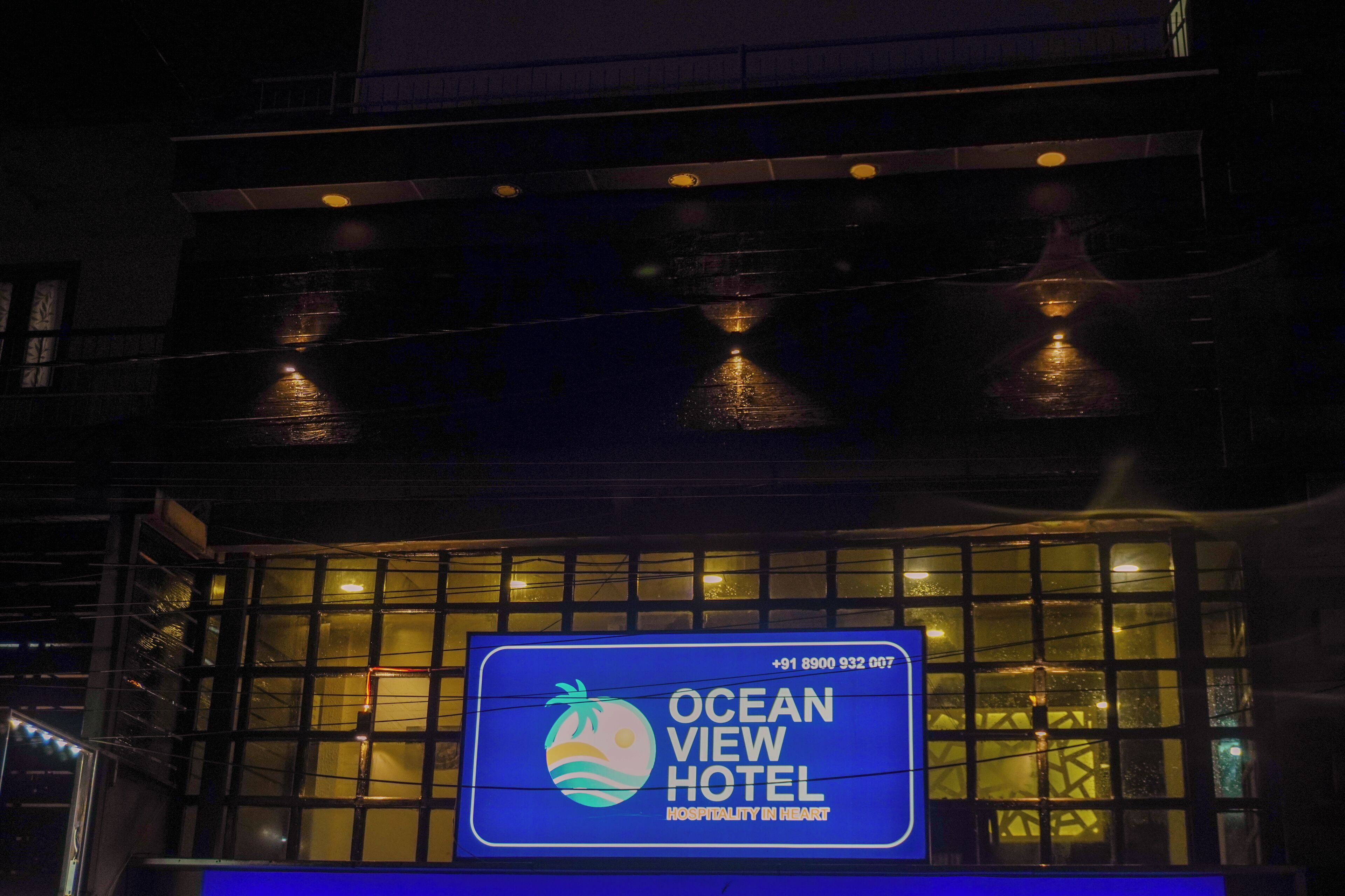 The exterior of the Ocean View Hotel with a large illuminated sign displaying the hotel's name and contact number.