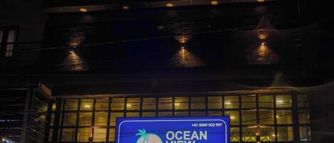 The exterior of the Ocean View Hotel with a large illuminated sign displaying the hotel's name and contact number.