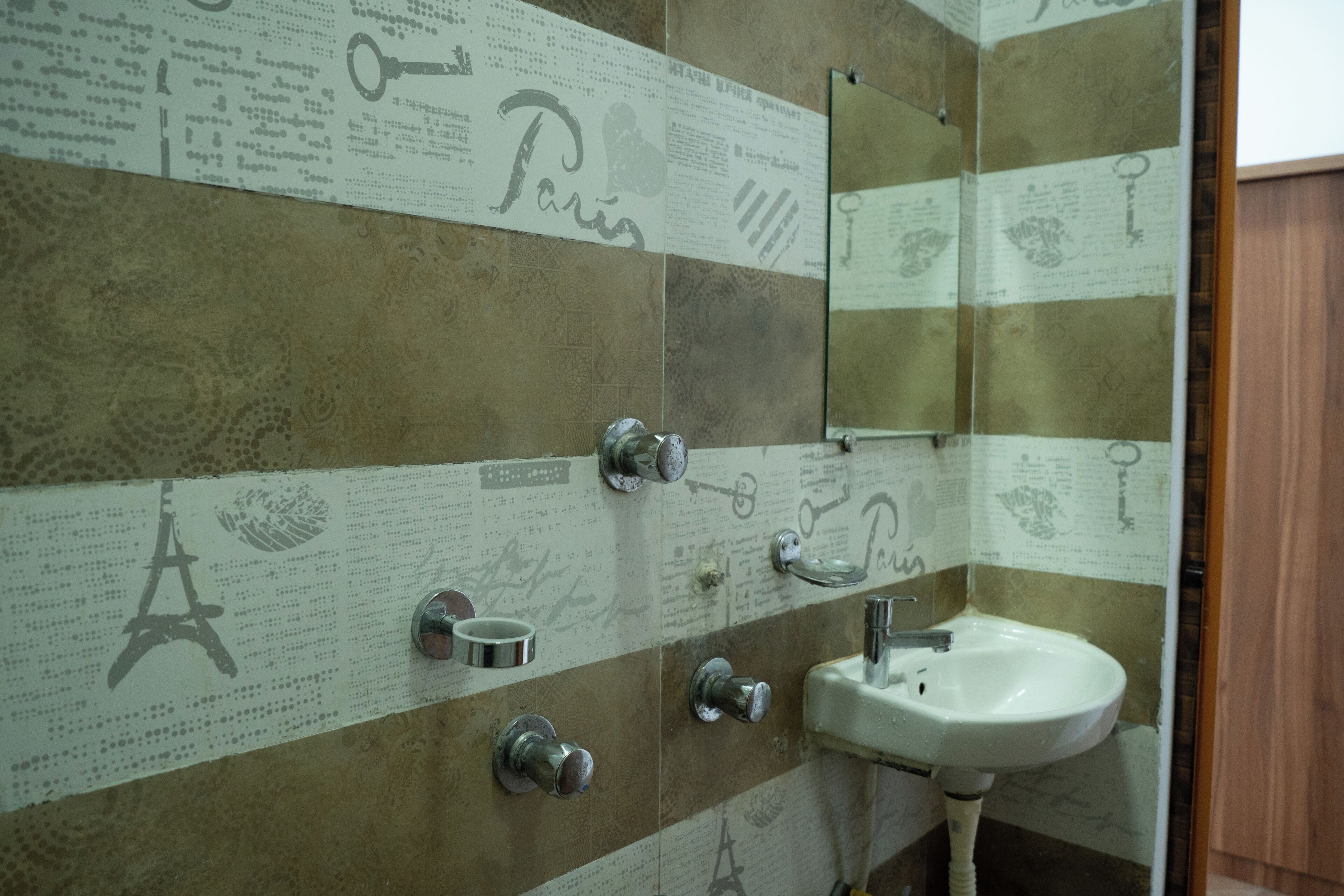 A bathroom with a tiled wall featuring Paris-related designs, a sink, and a mirror.