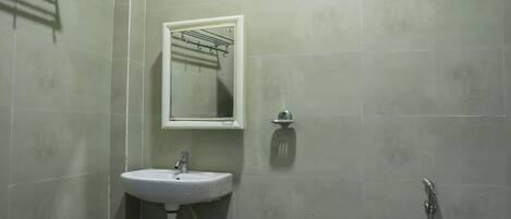 A bathroom with a sink, mirror, and shower.