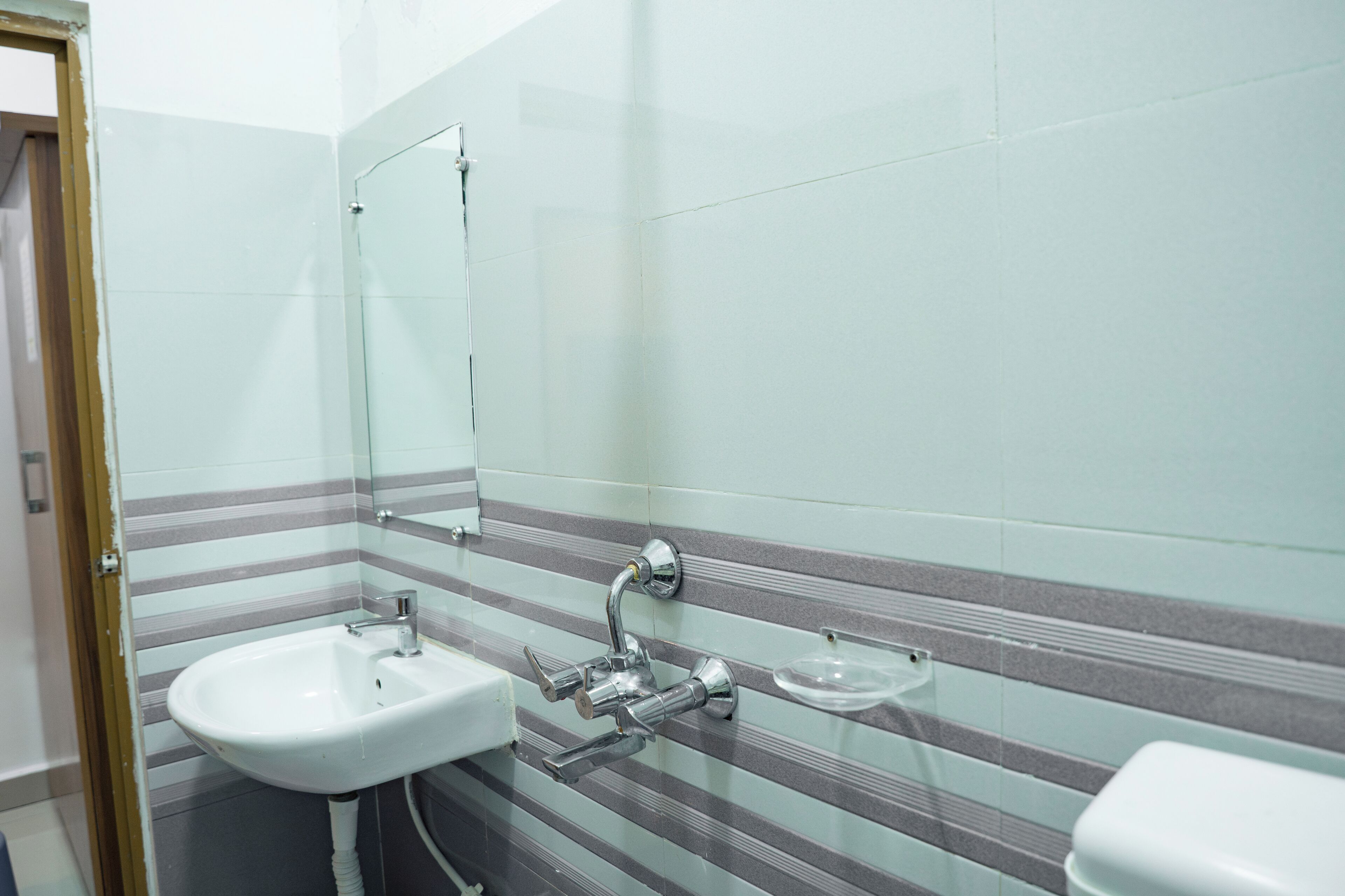 A bathroom with a white sink, a mirror, and a glass soap dish.