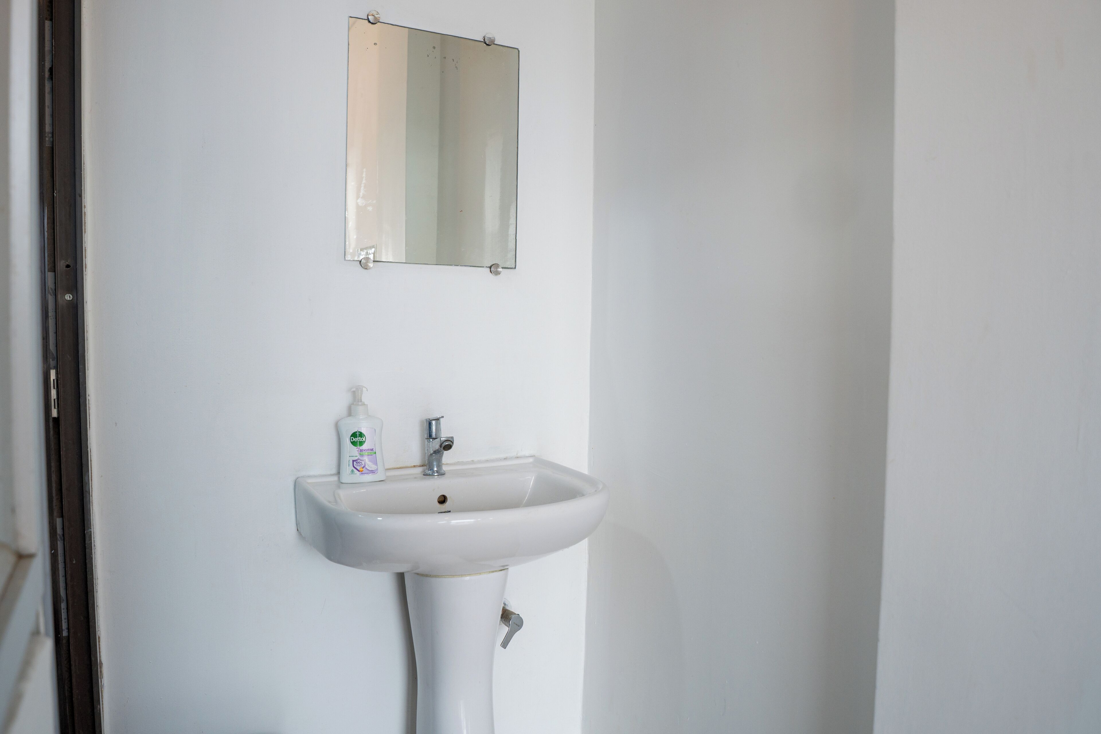 Un bagno in bianco con un lavabo e uno specchio sopra.