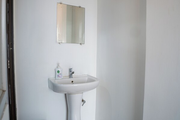 A white bathroom with a sink and a mirror above it.
