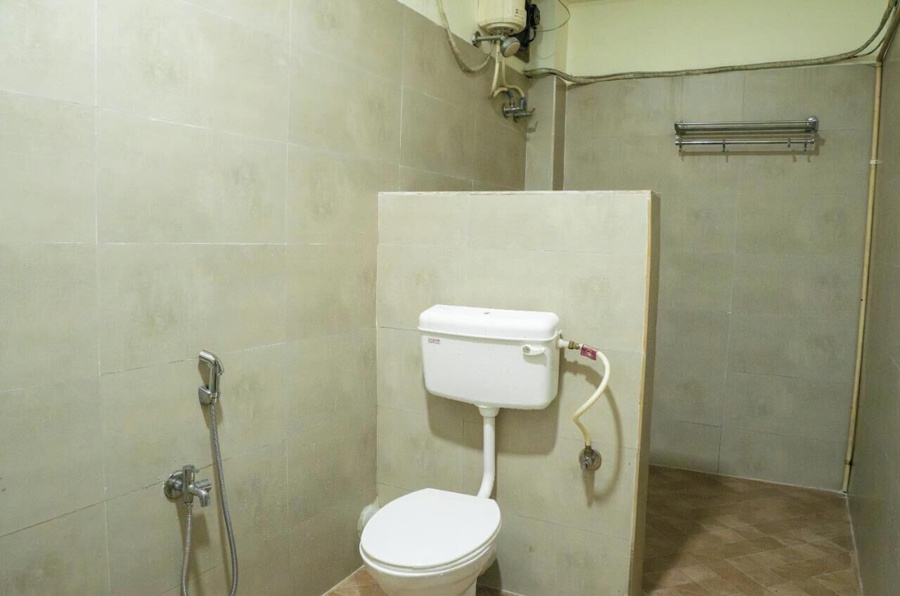 A small, enclosed bathroom with a toilet, a shower, and a towel rack.