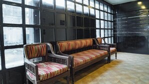 A seating area with a bench and two chairs, large windows, and a tiled floor. - Ocean View (Port Blair)