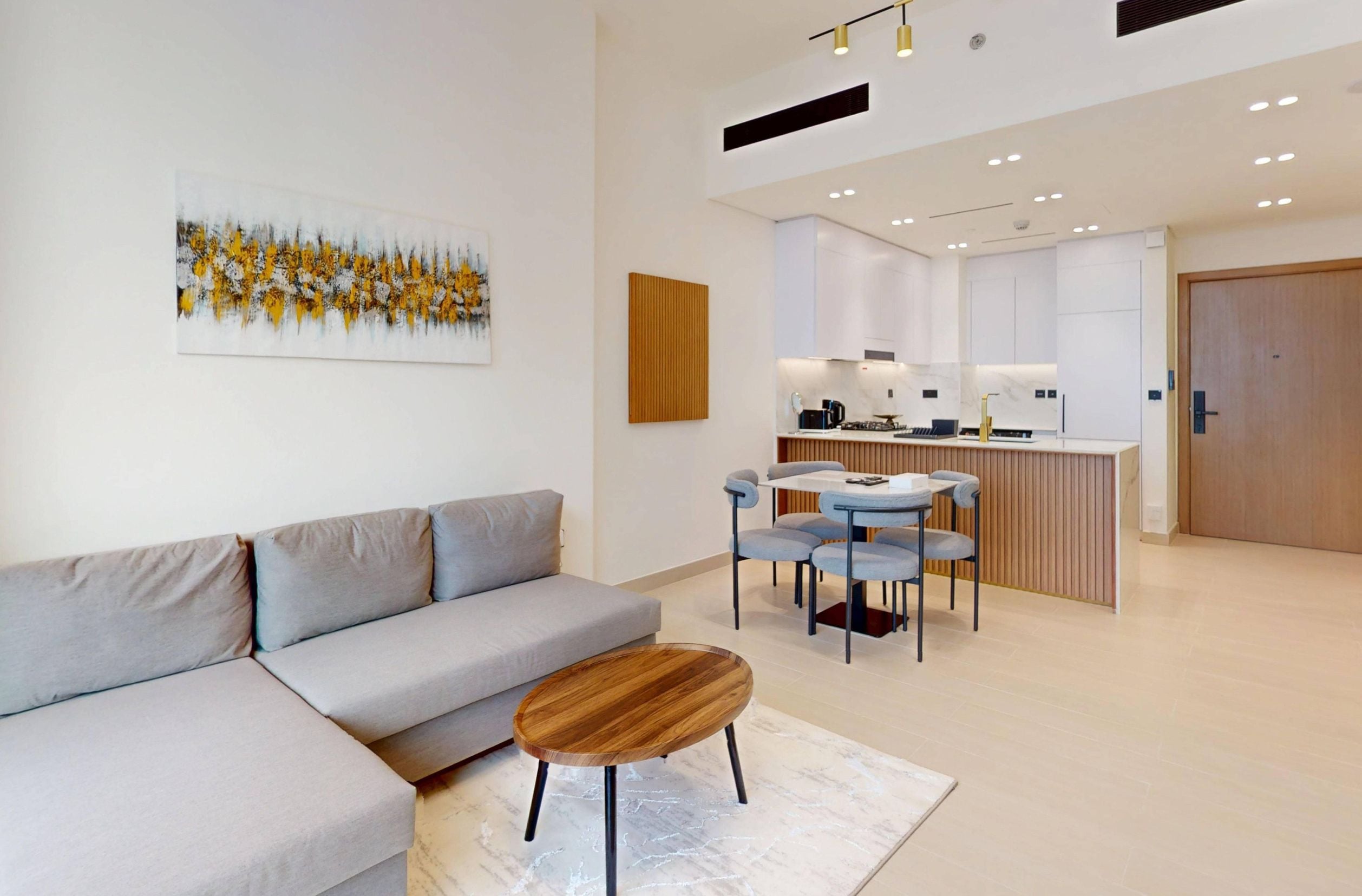A modern living room with a grey sofa, a wooden coffee table, and a painting on the wall.