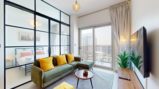 Una sala de estar moderna con un sofá verde, una mesita redonda y un amplio ventanal con vistas a la ciudad.