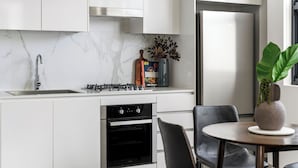 A modern kitchen with white cabinetry, a stainless steel range, and a built-in oven.