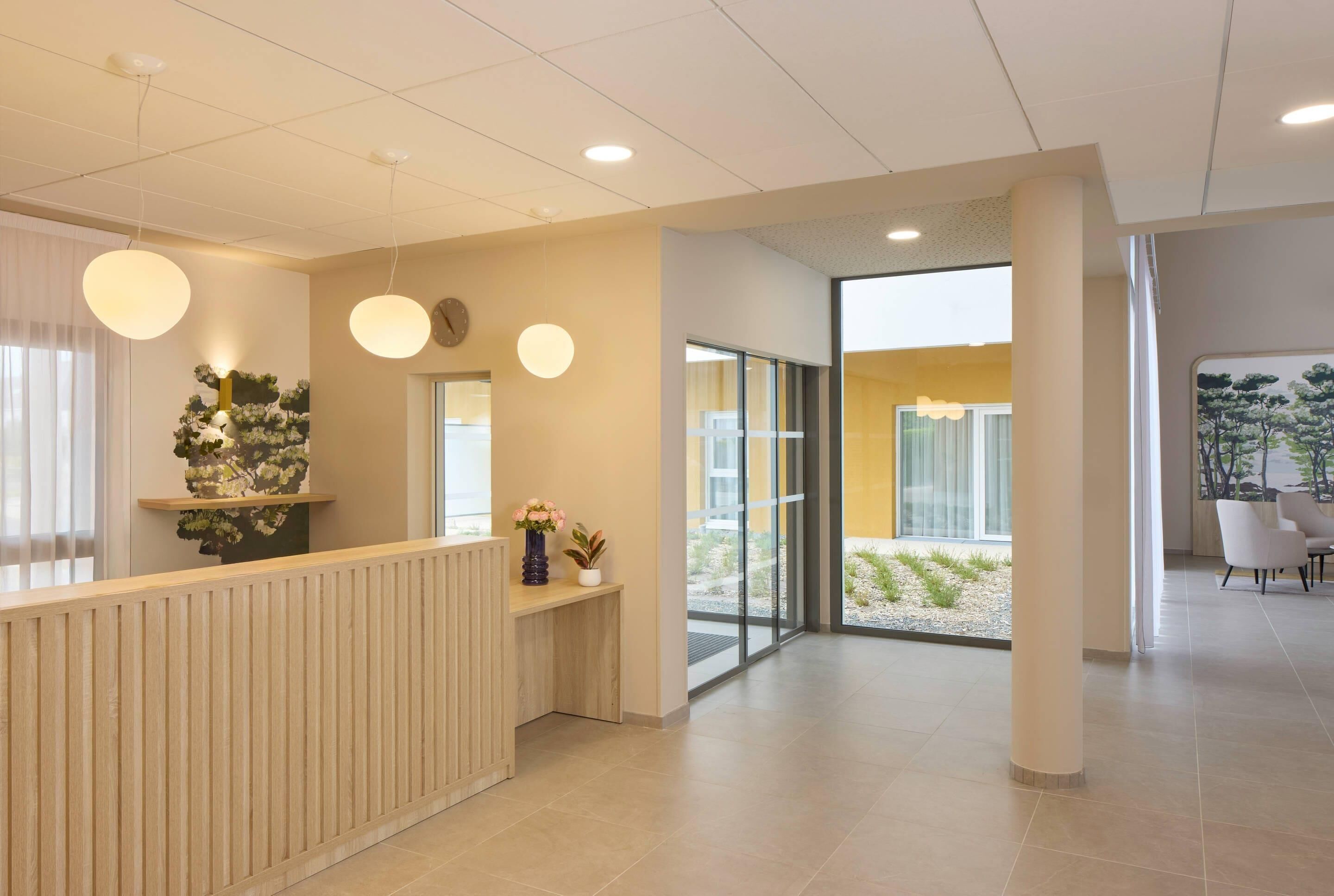 A modern reception area with a wooden reception desk, round pendant lights, and a large glass door leading outside.