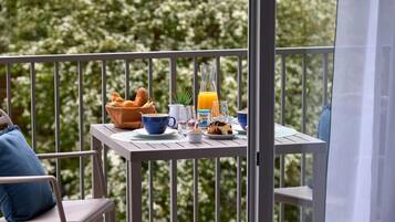 A balcony with a table set for breakfast, including bread, a jug of orange juice, and a plate of food.