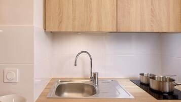 A kitchen with a stainless steel sink, wooden cabinets, and a black induction cooktop.