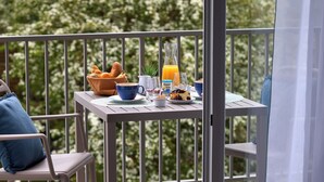 Een balkon met een ontbijtarrangement, inclusief brood, een drankje en een plant.