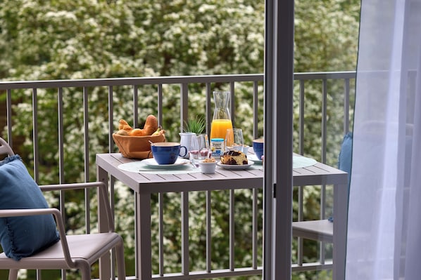 A balcony with a breakfast setup including bread, a drink, and a plant.
