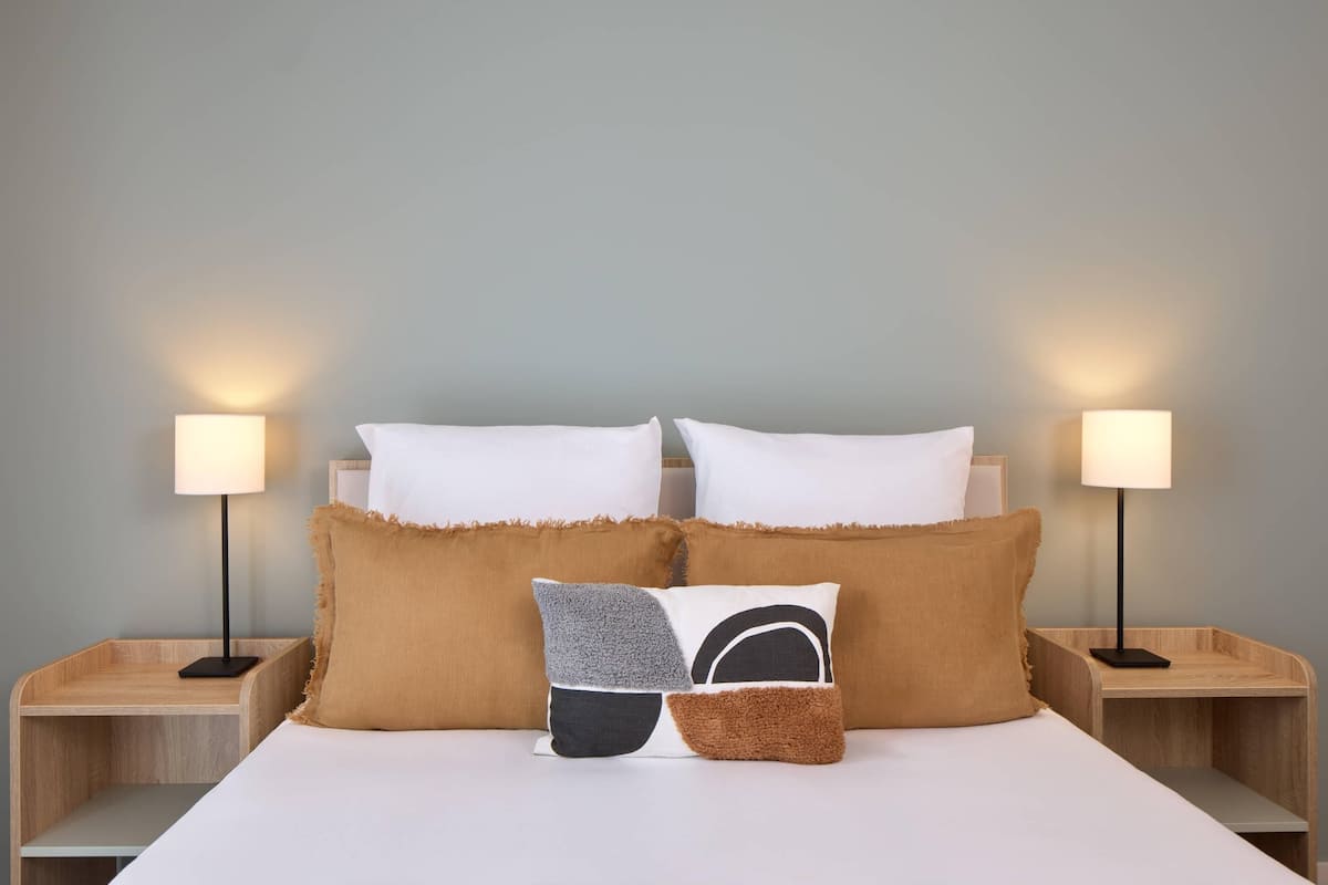 A neatly made bed with white linens and two bedside lamps on wooden nightstands.