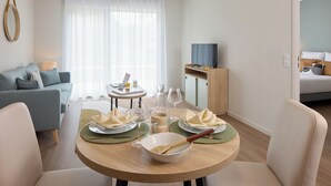 Een moderne woonkamer met een eethoek, een bank, een televisie en een bed.