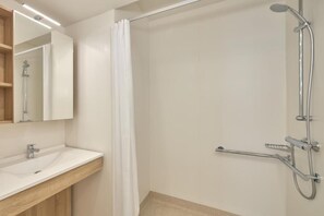 A modern bathroom with a shower, a sink, and a mirror.