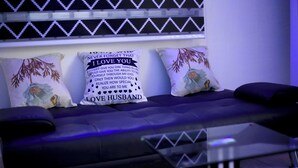A modern living room with a sofa set, two decorative pillows with text, and a patterned wall. - Luxurious Lukes Apartment (Benin City)