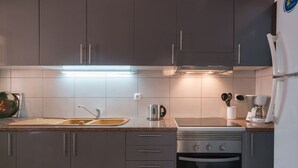 Eine moderne Küche mit grauen Schränken, einer Edelstahl-Spüle, einem Wasserkocher, einer Kaffeemaschine und einem Backofen.